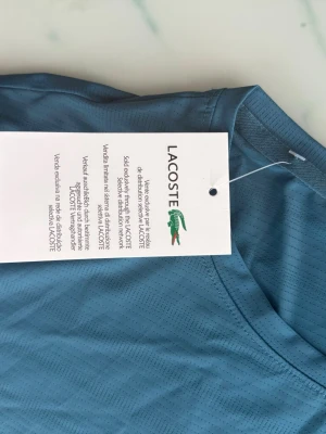 Lacoste Sport T-shirt  - Säljer en Lacoste Sport T-shirt i storlek . Ny med tagg och aldrig använd. Stretchigt material som passar bra till träning eller vardag. Kan skickas i hela Sverige. 100% säker frakt. Storlek är M.