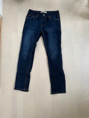 Levis jeans - Snygga mörkblå jeans med raka ben och klassisk femficksdesign. Jeansen har kontrastsömmar och knappgylf. Materialet är denim i bomull och passformen är normal. Perfekta till en avslappnad stil. Storlek W29 L30 