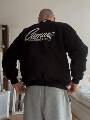 Chevrolet Camaro jacka - Säljer en jacka med Chevrolet Camaro motiv. Alla loggor på jackan är broderade. Den är i superfint skick utan några tecken på användning. Längden är 72,5cm och axelbredden är ca 52cm