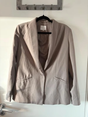 Beige kavaj - VILA kavaj i beige/taupe, storlek 40. Klassisk modell med en knapp och fodrad insida. Använd men i fint skick. Mindre tecken på användning i form av några små tråddragningar (se närbild), i övrigt hel och fräsch.                                      Har bundle-rabatt så kolla gärna in min sida. Buda gärna🧡