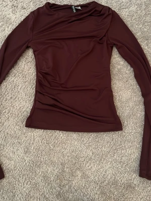 Mörkröd långärmad topp - Snygg mörkröd långärmad topp med figurnära passform. Toppen har en enkel design utan synliga detaljer och är perfekt att styla till olika outfits. Materialet känns mjukt och stretchigt.