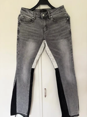 Grå jeans med kontrastpaneler SIARR - Unika grå jeans från SIARR med svarta och vita kontrastpaneler längs benen. Raka ben med råa kanter nertill och klassisk femficksmodell. Jeansen har en cool tvättad look och är tillverkade i denim. Perfekta för dig som vill sticka ut. Använd under 2 månader