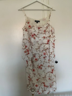 Vit blommig långklänning Lauren Ralph Lauren - Vit långklänning från Lauren Ralph Lauren med tunna axelband och ett romantiskt blommönster i rosa och grönt. Klänningen har en luftig passform och är perfekt för varma dagar. Tillverkad i ett mjukt, lätt material som känns skönt mot huden. St 14 men passar 38-40. 