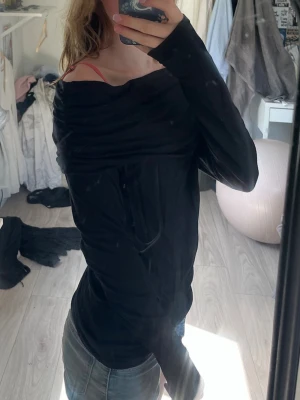 Svart offshoulder långärmad topp - Säljer en svart offshoulder topp med långa ärmar. Toppen har en bred, vikt krage som ger en snygg och avslappnad look. Perfekt att styla med jeans eller kjol för en trendig outfit.