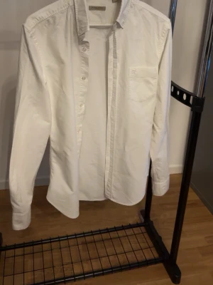 Vit skjorta från Burberry Brit - Klassisk vit skjorta från Burberry Brit med bröstficka och knappar framtill. Skjortan har lång ärm och en stilren, tidlös design. Perfekt till många olika looks och enkel att matcha. Tillverkad i mjuk bomull för skön känsla. Använts 1-2 gånger.