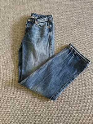 Blå raka jeans från Weekday Arrow - Säljer ett par blå raka jeans från Weekday, modell Arrow. Jeansen har klassisk femficksdesign, hög midja och är tillverkade i 100% bomull. Perfekta för en avslappnad och trendig look.