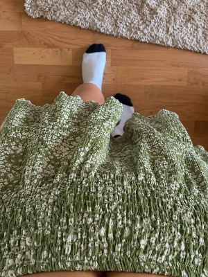 Grön blommig kortkjol med volang - Söt grön kortkjol med små vita blommor och volangkant. Kjolen har smock i midjan. Har använt den cirka 4 gånger 
