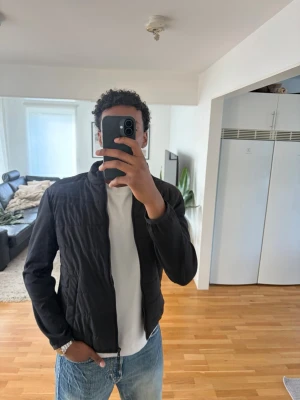 Svart quiltad Cardigan från Zara - Säljer en svart quiltad cardigan med rak passform och diskret ståkrage. Jackan har dragkedja framtill och är lätt vadderad, perfekt för lager på lager. Enkel och stilren design som passar till det mesta. Storlek L men den är lite liten i design passar t M skulle jag påstå.