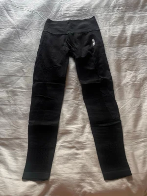 Svarta seamless leggings Gymshark - Säljer ett par svarta seamless leggings från Gymshark med hög midja och diskret logga på höften. Materialet är stretchigt och har snygga ribbade detaljer längs benen för extra stilpoäng. Perfekta för träning eller chill dagar.