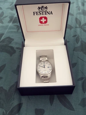 Festina Klocka - Klocka i silver, med vit dial o blå detaljer. Använd en gång, men syns inte. Automatisk. Köptes för 1200kr. 