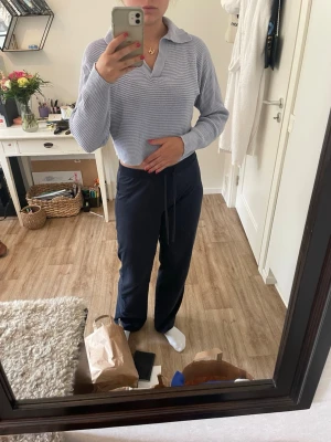 Ljuslila stickad tröja med krage - Säljer en ljuslila stickad tröja med krage och v-ringning. Tröjan har långa ärmar och är ribbstickad för en avslappnad men ändå stilren look. Perfekt att matcha med jeans eller kostymbyxor för en trendig vardagsstil.