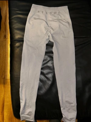  Relode - Snygga grå tights från Relode med hög midja och scrunch-detalj bak. Tillverkade i ett stretchigt och mjukt material som passar perfekt för träning eller gym. Diskret logga i midjan och tight passform för en sportig look. Har en liten lagning därav pris se bild. Lapparna är bortklippta skulle säga xs/s 
