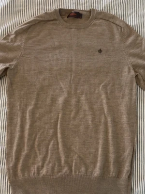 Beige Morris tröja - Stilren Morris-tröja i mjukt och bekvämt stickat material. Perfekt både till vardag och mer uppklädda outfits. Enkel att matcha och sitter riktigt snyggt på kroppen. Storlek XL men sitter något mindre.✨  Vid intresse är det bara att lägga ett bud eller skriva vid minsta fråga eller fundering 🔥