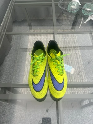 Nike Hypervenom Phatal AG 42 - Säljer ett par Nike Hypervenom Phatal AG i storlek 42. Klassiska neongula Hypervenom med blå Swoosh – en ikonisk modell som inte längre tillverkas och är eftertraktad bland fotbollsspelare.  AG-sula för konstgräs med bra grepp, låg vikt och hög komfort. Skorna är i fint begagnat skick med normalt slitage och fungerar utmärkt till både träning och match.  ⚽ Storlek: EU 42 👟 Modell: Hypervenom Phatal AG 🌱 Underlag: AG (konstgräs) ✅ Fint begagnat skick  Skickas snabbt eller möts upp vid behov.
