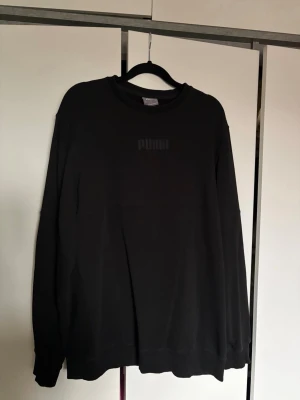 Svart sweatshirt från Puma - En stilren svart sweatshirt från Puma med diskret broderad logga på bröstet.