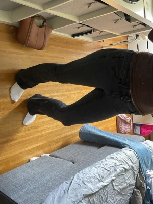 Svarta bootcut jeans - Säljer ett par svarta bootcut jeans med klassisk femficksmodell och låg midja. Jeansen har en snygg utsvängd passform. Materialet är denim med lite stretch för extra komfort.