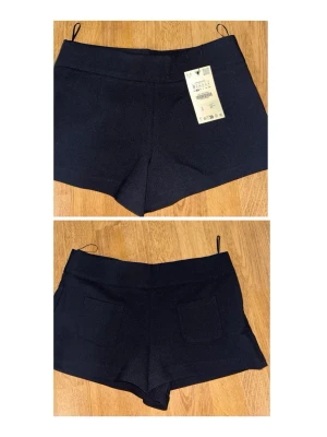Svarta höga shorts med fickor - Stilrena svarta shorts med hög midja och två bakfickor. Klassisk design med enkel passform och utan synliga detaljer framtill. Perfekta till sommaren och lätta att matcha med olika toppar.