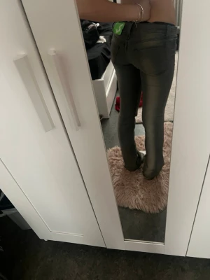 Grå bootcut jeans med låg midja - Grå jeans med låg midja och bootcut passform. Jeansen har klassisk femficksdesign och stängs med knapp och dragkedja. Materialet ser ut att vara stretchig denim som sitter snyggt och bekvämt.