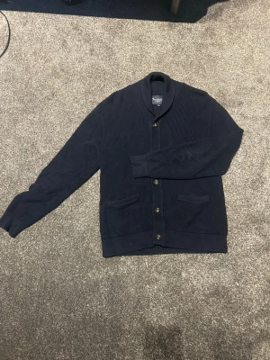 Overshirt - Mörkblå stockad overshirt, cardigan tröja, stilren och bra skick lite dammig och så men tvättas och stryks innan leverans. Stilig och går med många outfits . Pris ej hugget i sten, stl S 
