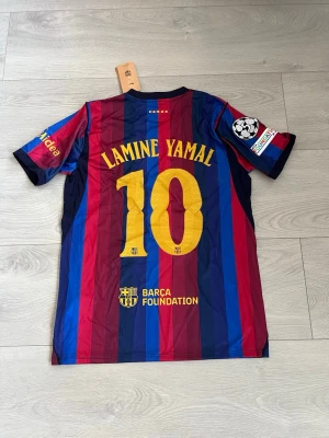Barcelona tröja 26/27 - Säljer en fin barca tröja säsongen 26-27 med Lamine Yamal på ryggen! Tröjan är i storlek M och är oanvänd!!