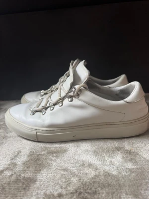 Diemme skor - Stilrena vita sneakers med robust sula och unika metallhål för snörningen. Skorna har en låg profil och är tillverkade i slätt läder. Passar perfekt till streetwear och ger en clean look till outfiten.