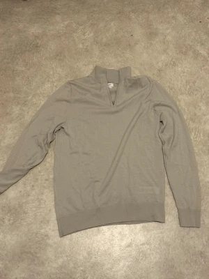 Halfzip från Autograph - Snygg beige stickad tröja från Autograph i extra fin merinoull. Tröjan har halv dragkedja vid halsen och långa ärmar. Perfekt för dig som gillar stilrena och mjuka plagg med hög komfort.