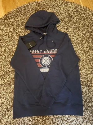 Saint laurent - Hej säljer en riktigt fet och populär saint Laurent hoodie i storlek M. Hoodien är oanvänd och hör av er vid frågor!!!