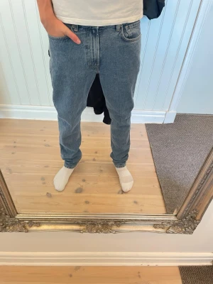 Ljusblå jeans från taktil - Säljer ett par klassiska blå jeans med rak passform. Jeansen har fem fickor, bälteshällor och stängs med dragkedja och knapp. Ny med prislapp på som ses på bilden, storlek 29/30. Modellen på bilden är 183. Hör av er vid funderingar!