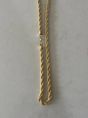 Guld kordell halsband från kejsar - Säljer ett snyggt guldfärgat halsband med tvinnad kedja. Köpt för 1229kr Halsbandet har en klassisk karbinhake och känns riktigt stilrent och trendigt. Perfekt för dig som gillar accessoarer med lite extra edge och vill lyfta din outfit med en guldig detalj.