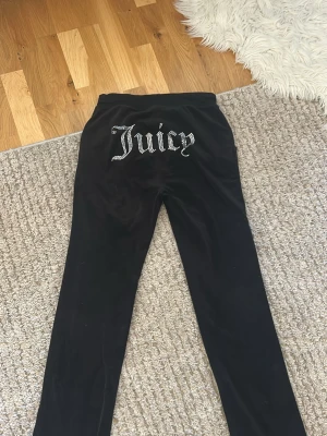 Juicy Couture mjukisbyxor - Säljer ett par jätte sköna svarta mjukisbyxor från Juicy Couture i velour med text på rumpan. jag använder byxorna inte längre och det är anledningen till att jag säljer dem!❤️