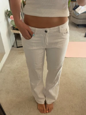 Low waist jeans vita - Säljer ett par vita jeans med rak passform och låg midja. Jeansen har klassiska fem fickor och stängs med knapp och dragkedja. Materialet ser ut att vara denim i bomull. Perfekta för en clean och fräsch look.
