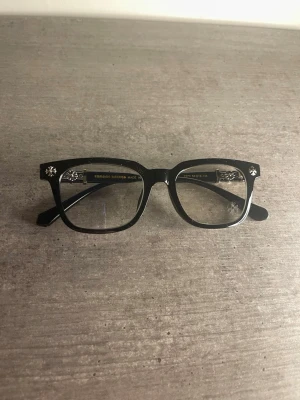 Svarta blåljus glasögon med silverdetaljer - Snygga svarta solglasögon med rektangulär form och coola silverfärgade detaljer vid gångjärnen. Bågarna är i plast och har en stilren look som passar till det mesta. Perfekta för dig som vill ha en trendig accessoar med lite extra edge.