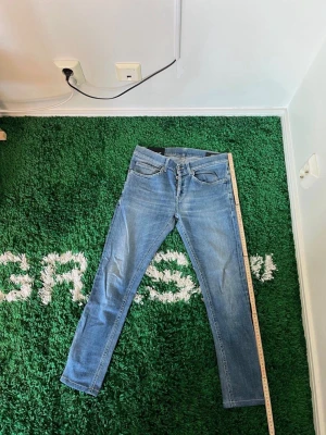 Dondup George Ljusblå slim fit jeans - Säljer ett par ljusblå Dondup George jeans med klassisk femficksdesign och dragkedjegylf. Jeansen har en snygg tvättad look och smala ben som sitter tajt hela vägen ner. Perfekta för dig som gillar en modern och enkel stil. Storlek 30, men observera benlängden då dem är upplagda. 