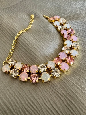Armband med rosa och vita stenar - Snyggt armband i färgerna: rosa, rosa opal, vit opal, crystal. Kedjan guldfärgad, justerbar cirka 17-24 cm.  Aldrig använt, mycket bra skick.