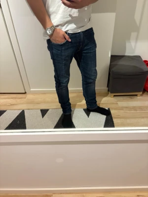 Levis 512 - Säljer ett par mörkblå slim fit jeans med klassisk femficksdesign och raka ben. Jeansen har diskreta slitningar och kontrastsömmar. Passar perfekt till en avslappnad stil och är tillverkade i ett mjukt denimtyg.