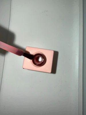 Rosa nagellack i fyrkantig flaska - Nagellack i en fyrkantig flaska med ljusrosa lock. Färgen är en mjuk, dammig rosa nyans som ger ett elegant intryck. Penseln är smidig och gör det enkelt att måla naglarna jämnt. Perfekt för dig som gillar stilrena och feminina toner.