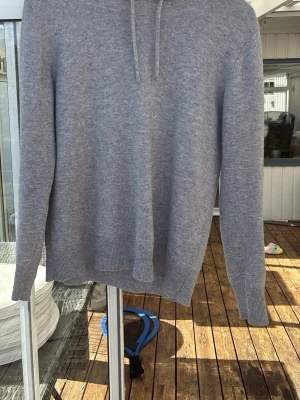 Sayless hoodie - En stilren ljusgrå hoodie med huva och dragsnören. Tillverkad i mjukt stickat material som känns skönt mot huden. Hoodien har långa ärmar och ribbade muddar vid ärmslut och nederkant. Perfekt för en avslappnad look.