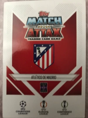 Match Attax Atlético de Madrid kort - Samlarbild från Topps Match Attax med Atlético de Madrid-tema. Ena sidan visar klubbens logga och turneringar, andra sidan har spelaren Rodrigo De Paul i rödvitrandig matchtröja. Kortet har vita och röda färger och är gjort av glansigt papper.