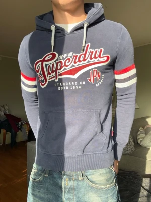 Superdry vintage hoodie - Sjukt snygg superdry hoodie!🤩 Väldigt go passform samt fina färger. Väldigt bra skick, dock så har det lossnat lite material på ärmarna, syns på bild. Tänker inte på det i verkligheten dock. Passar som XS. Tveka inte på att ställa frågor eller skicka prisförslag!🤩