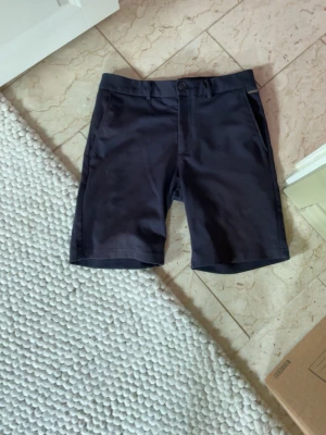 Svarta klassiska shorts - Snygga svarta shorts med normal passform och midwaist. De har enkel design med knapp och dragkedja framtill samt sidfickor. Perfekta för sommaren och passar till det mesta.
