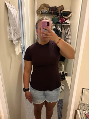 Mörkröd figursydd T-shirt - En enkel och stilren mörkröd T-shirt med rund hals och korta ärmar. T-shirten har en figursydd passform och är gjord i ett tjockare material, perfekt till jeans, kjol eller shorts. Inga tryck eller detaljer, bara clean och elegant. Storleken är xs men passar mig som är S/M