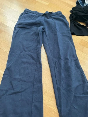Mörkblå mjukisbyxor från Gina Tricot - Mörkblå mjukisbyxor från Gina Tricot med rak passform och resår i midjan. Tillverkade i mjukt och bekvämt material, perfekta för chill dagar hemma eller när du vill ha en avslappnad stil.