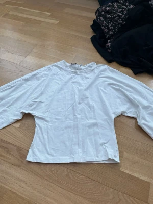 Vit långärmad topp i bomull - En enkel och stilren vit långärmad topp i mjuk bomull. Modellen har en rak passform och rund halsringning, perfekt att matcha med jeans eller kjol för en clean look.