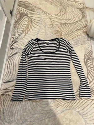 Randig långärmad topp i bomull - Säljer en klassisk långärmad topp med svarta och vita ränder. Toppen har rund halsringning och är gjord i mjuk bomull, perfekt för en enkel och stilren look. Passar till jeans eller kjol för en avslappnad vibe.