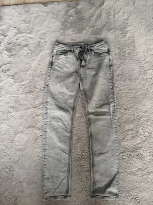 Grå slim fit jeans från gant - Snygga grå slim fit jeans med klassisk femficksdesign från gant  och raka ben. Jeansen har en ljus tvätt och svarta sömmar som ger en modern look. Perfekta för dig som gillar en stilren och enkel outfit.