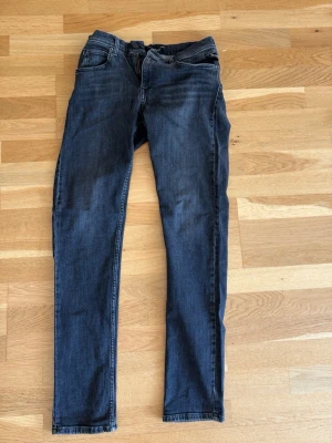 Svarta Replay jeans - Snygga svarta Replay jeans  med klassisk femficksmodell och normal midja. Jeansen har smal passform och är tillverkade i stretchigt denimtyg för extra komfort. Perfekta till en avslappnad streetstyle-look.