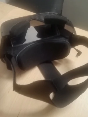 Svarta VR-glasögon med justerbart band - Säljer ett par svarta VR-glasögon med elastiskt justerbart band och vadderade kanter för extra komfort. Glasögonen har en plastfront med två linser och passar till mobiltelefoner för VR-upplevelser. Perfekt för gaming och 360-video.
