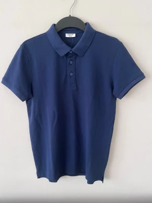 Mörkblå pikétröja från Kappahl  - Oanvänd piké tröja från Kappahl som köpts för 199kr.                                                                            Storlek 158/164