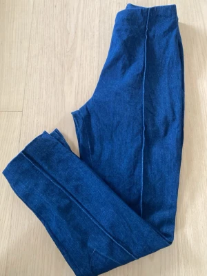 Mörkblå byxor i denim. - Snygga mörkblå jeans med smal passform och hög midja. Jeansen har raka ben med sydda pressveck. Dragkedja i sidan och en liten slits längst ner. Innerbenslängd 65 cm.