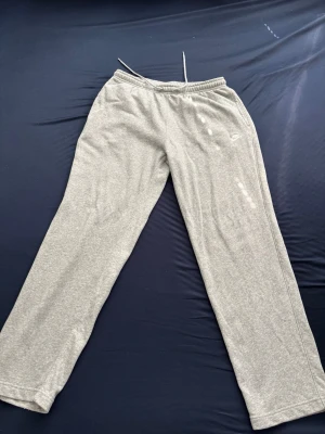 Grå träningsbyxor från Nike - Snygga grå träningsbyxor med raka ben och resår i midjan. Byxorna har en enkel design med diskret logga på sidan och en bakficka. Perfekta för träning